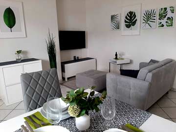 Wohnzimmer mit Sofa, TV und Esstisch