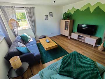 Wohn- und Schlafzimmer mit Sofa und TV