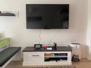 TV und links Esstisch mit Sitzbank im Wohnzimmer