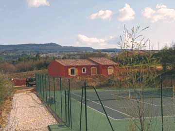 das Ferienhaus im Hintergrund und der Tennisplatz