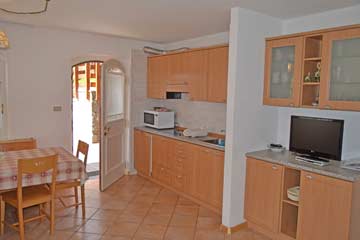 Wohnraum mit SAT-TV, im hinteren Bildbereich die Küche, links der Esstisch
