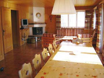 Wohnzimmer mit großem Esstisch, Sitzgruppe und offenem Kamin
